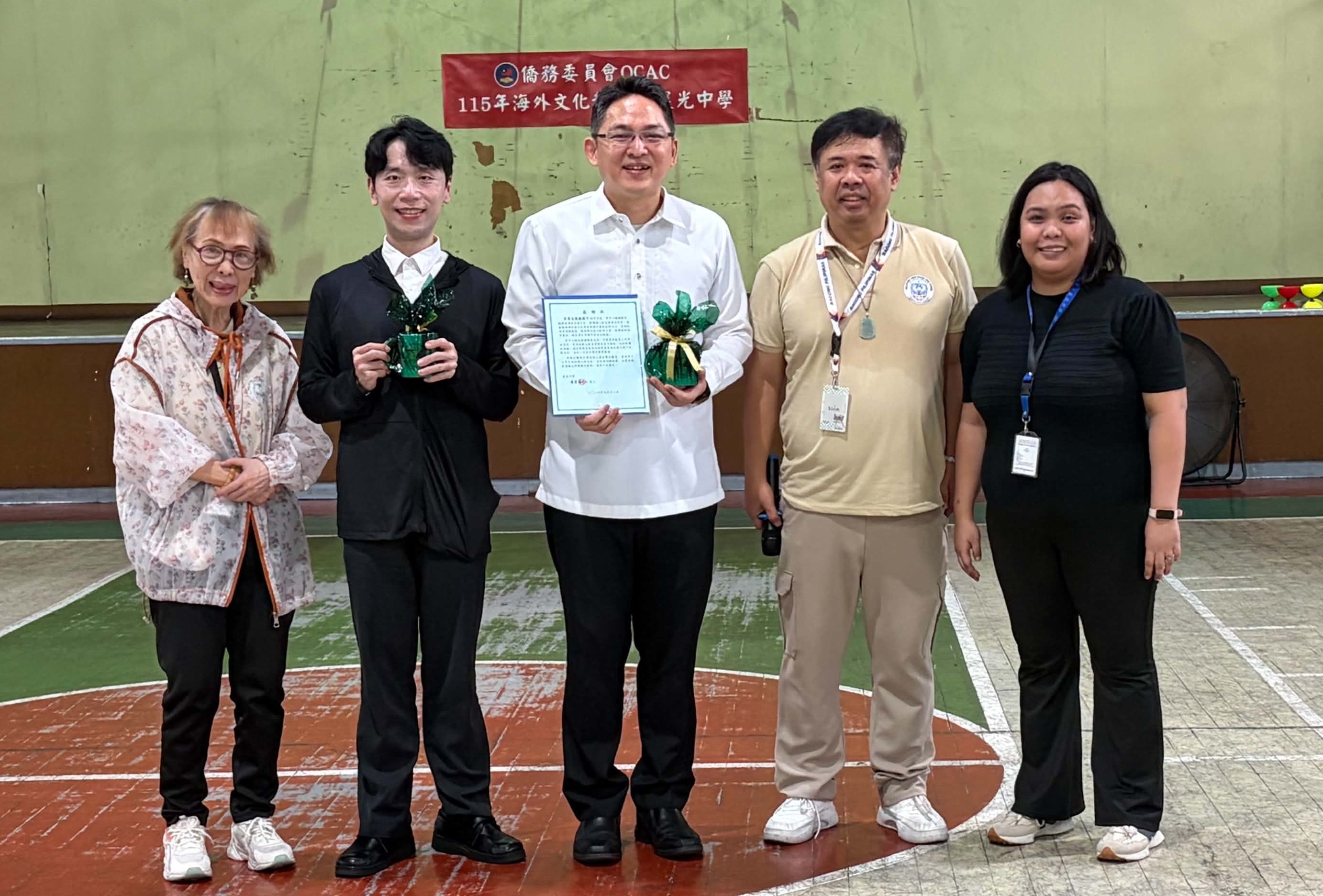 晨光中學貴賓與兩位文化巡迴教師於民俗技藝成果展前開心合影，為5天的文化巡迴教學留下美好紀念。