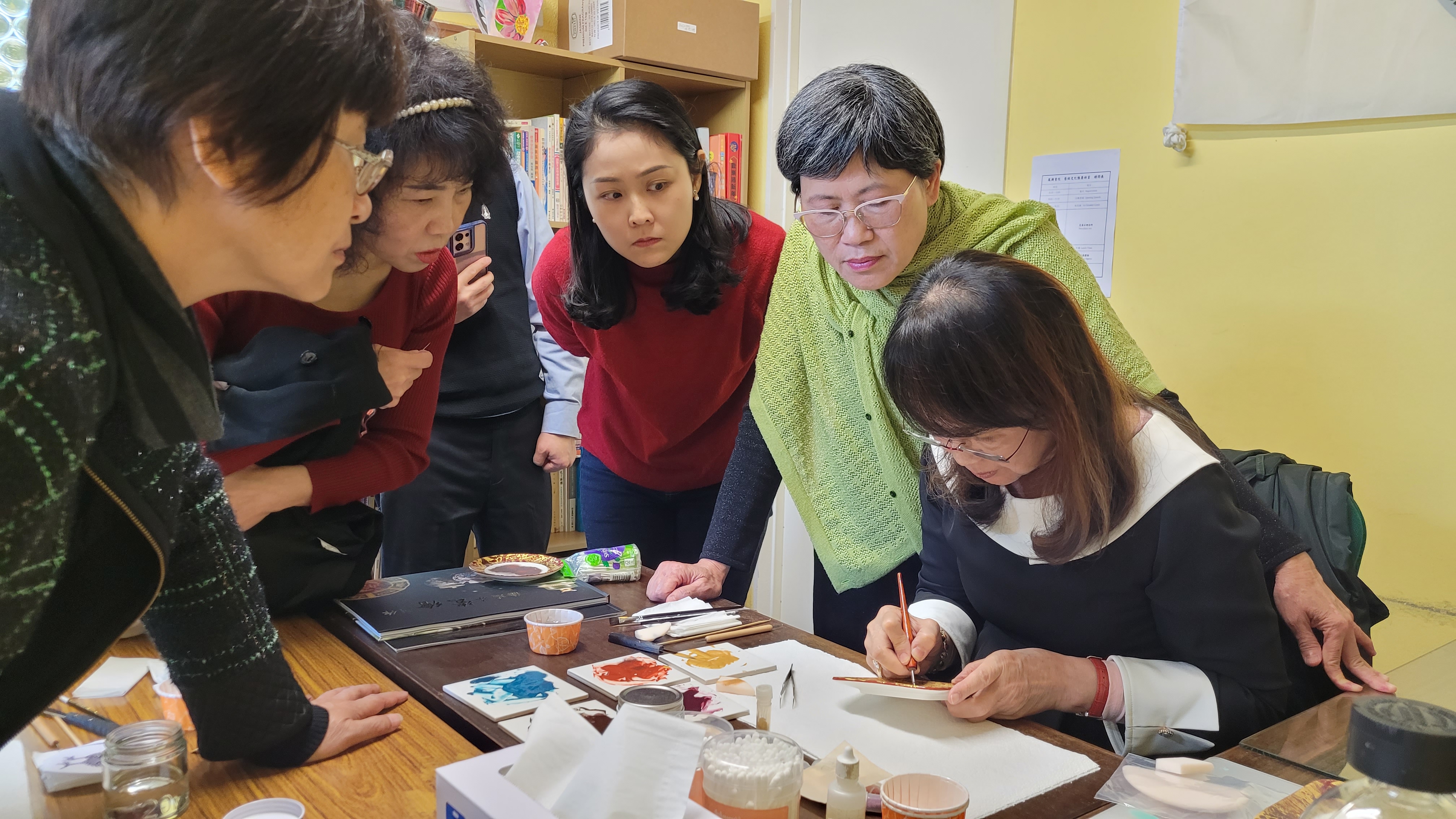 學員聚精會神觀看講師徐瑞芬（右1）示範瓷繪技巧