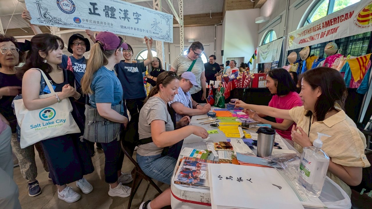 中華聯誼會(台灣)攤位前門庭若市，志工們用心指導訪客臨帖書法