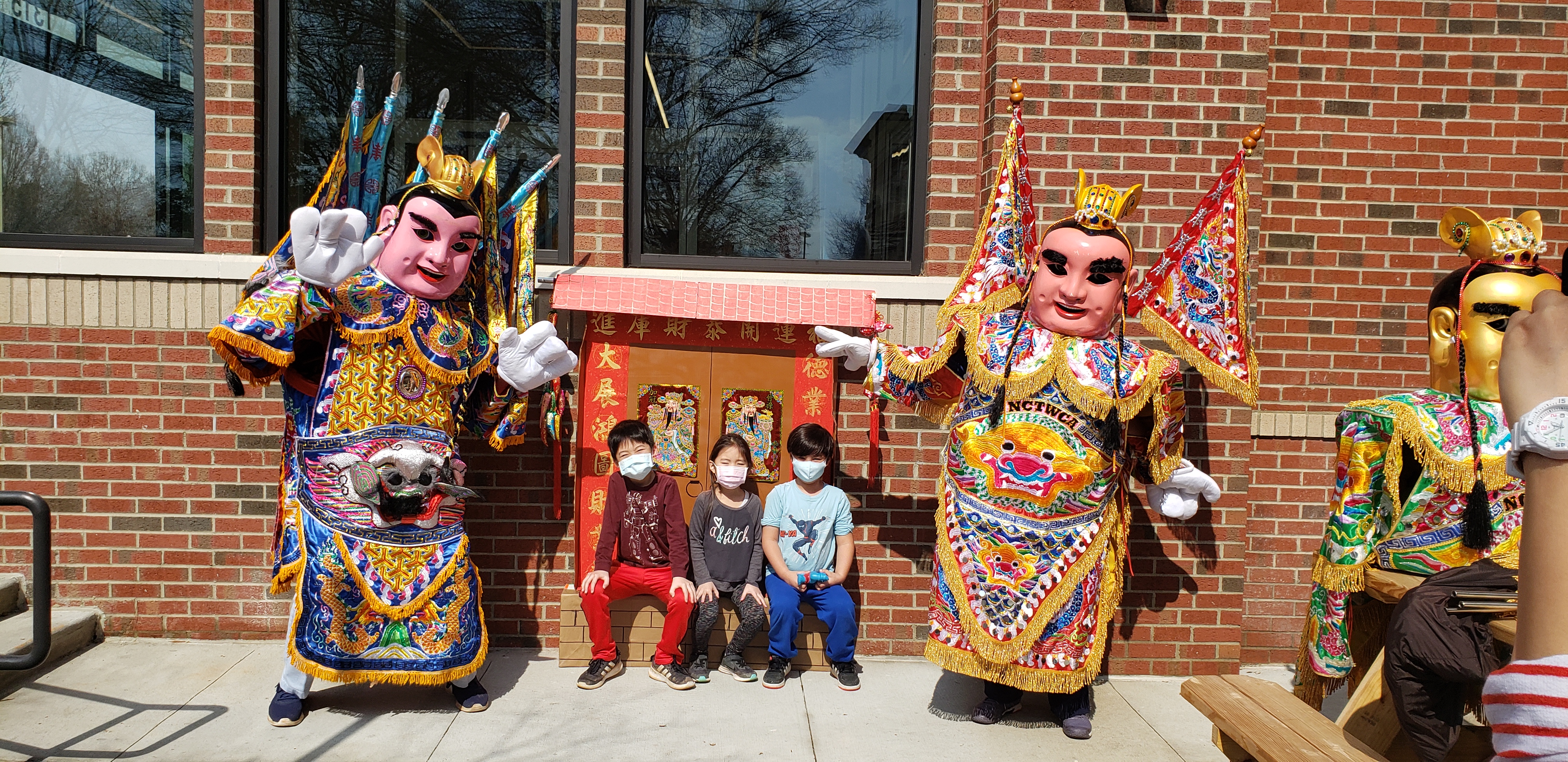 小朋友坐在古厝門前和三太子合照