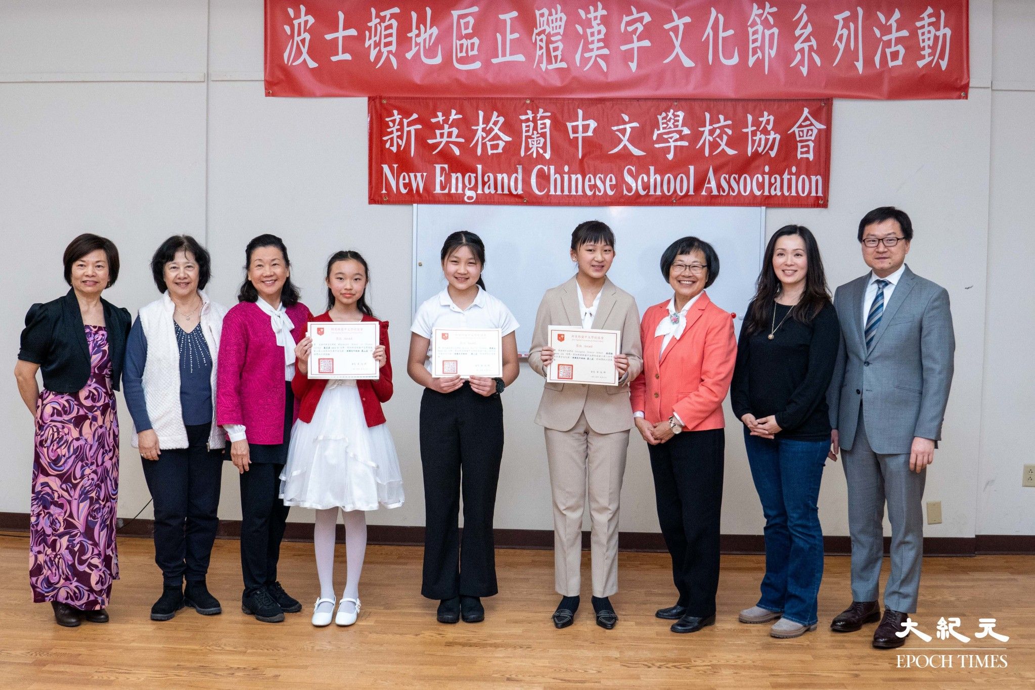 波士頓文教中心潘昭榮主任 (右一)，新英格蘭中文學校協會前會長王月娥老師 (左一) ，評審馮文鸞老師(左二)，評審吳萍萍老師(左三)，評審顏毓芬老師(右二)，主持人林梅英老師(右三)，及演講比賽高年級組得奬學生合影