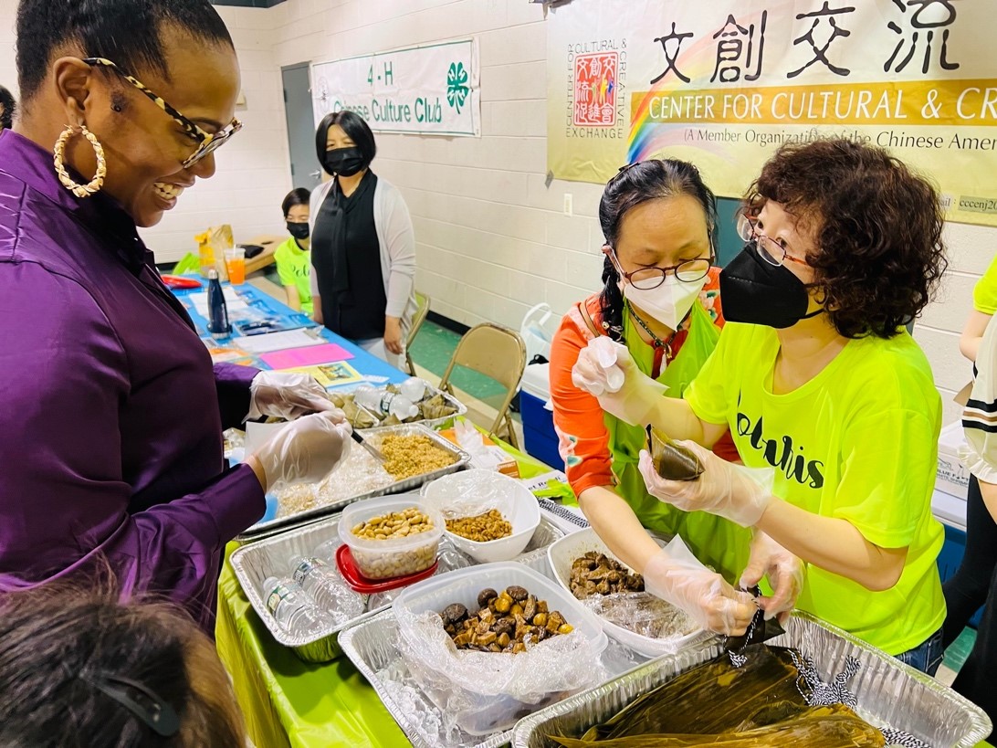 大家在園遊會的攤位上學習包粽子。