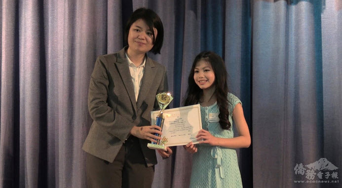 胡凱莉(右)演唱「揮著翅膀的女孩」，獲得中年級第一名，由紐約文教中心副王鈺淇(左)頒獎