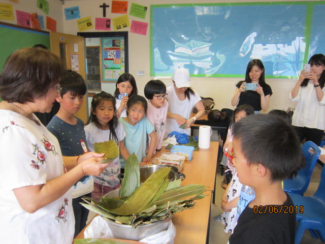 小朋友們聚精會神地一起學習包粽子感受過節氣氛。
