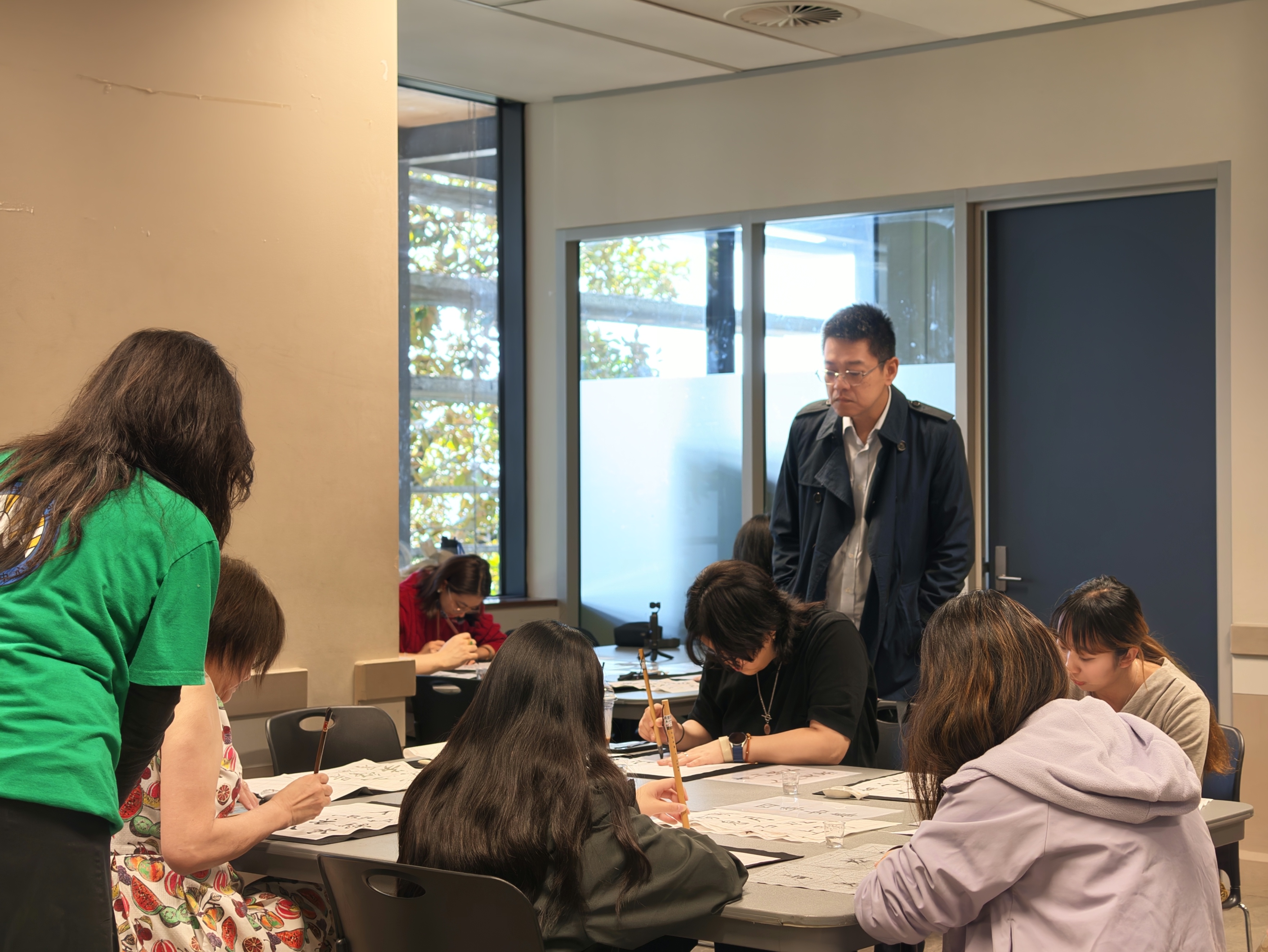 學員於上午文化工作坊專注練習毛筆運筆技巧，書法專家廖峻鋒名師現場觀摩並給予指導。