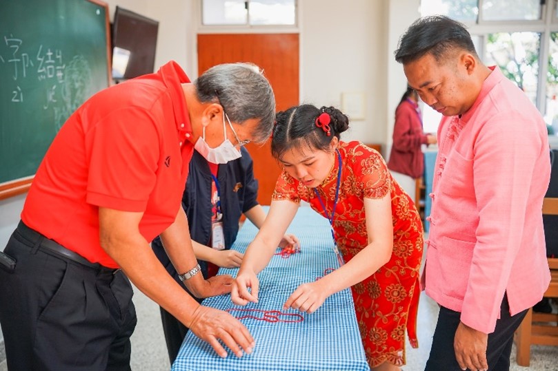 漢字也可以透過結繩的方法來呈現喔！前清邁教育局副局長認真的在學生說明下瞭解萬字結的意義和做法。