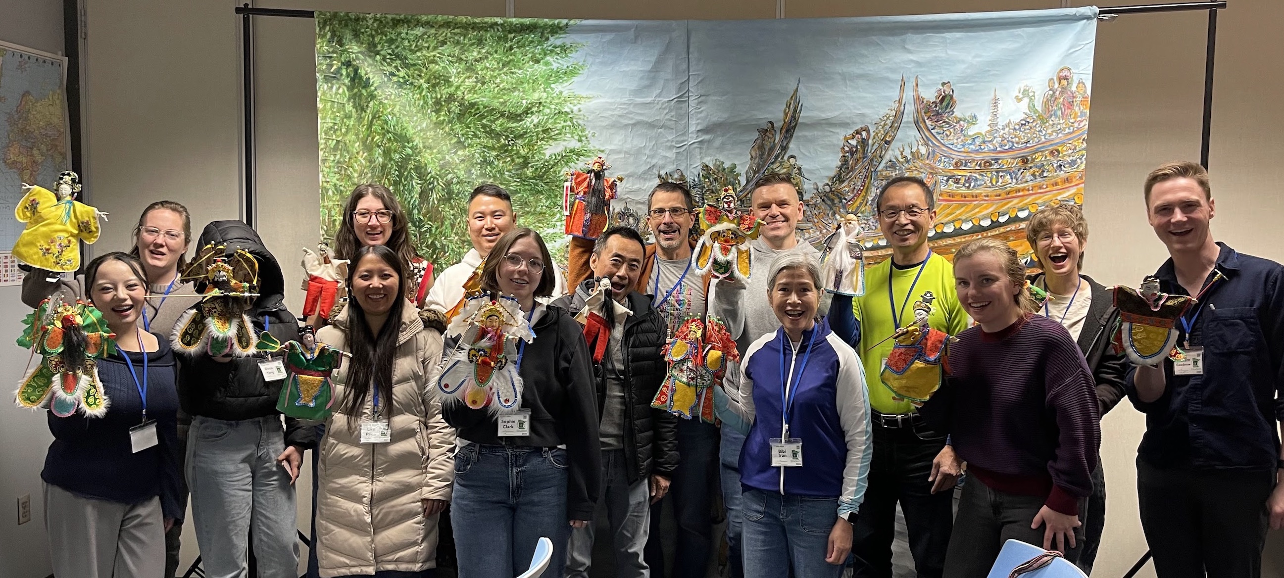 學員拿著布袋偶在臺灣廟宇油畫前合照