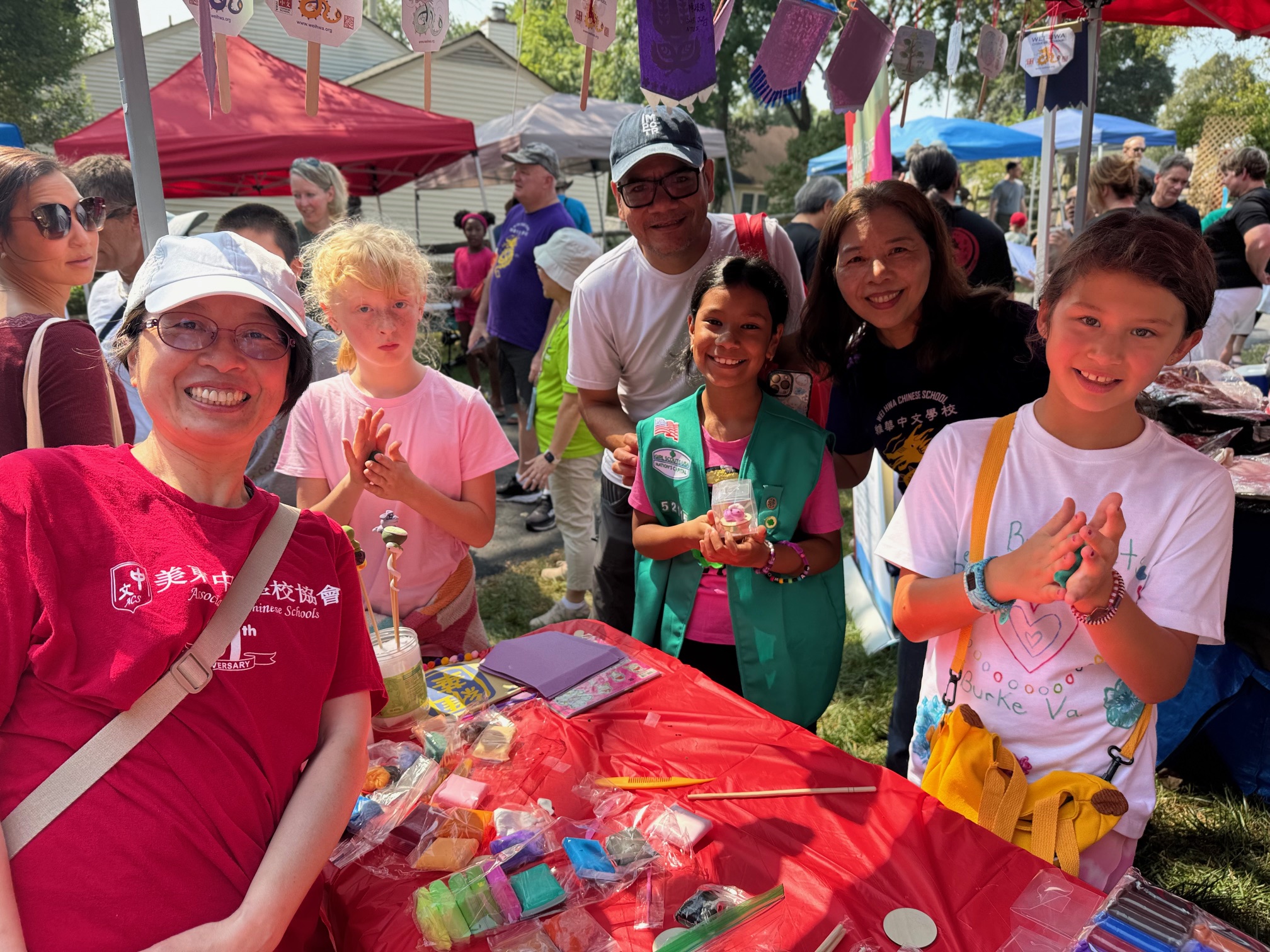 維華校長與捏麵人老師陳老師（Ms. Chen）與參與捏麵人手工藝的大小朋友合影，大家對傳統藝術興趣濃厚，笑容滿面，氣氛熱烈。