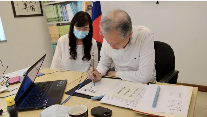 陳新苗老師(右)在鏡頭前示範隸書的寫法。