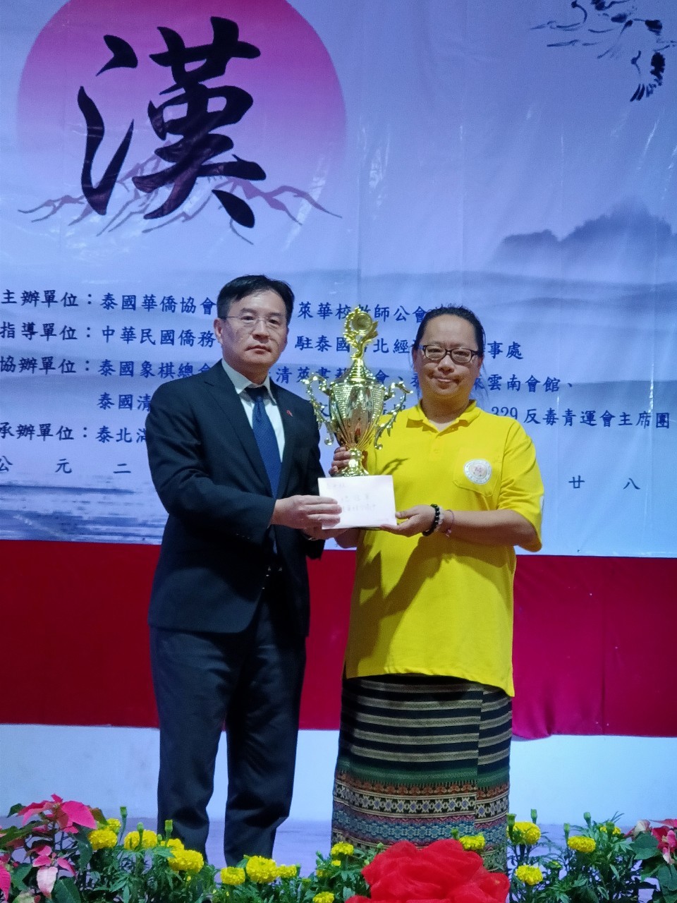駐泰僑務組高家富組長將高中組總冠軍獎盃頒給建華綜合高中梁梅華校長