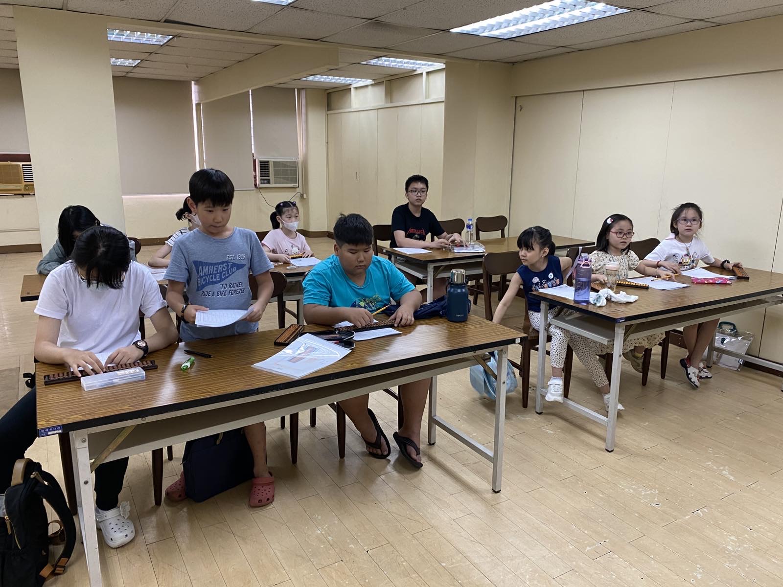 珠算課程課堂實景，學生們使用算盤進行基本運算訓練，展現高度學習興趣。