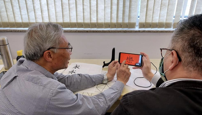 廖世秉老師(左)線上講評參加學員練習的字體。