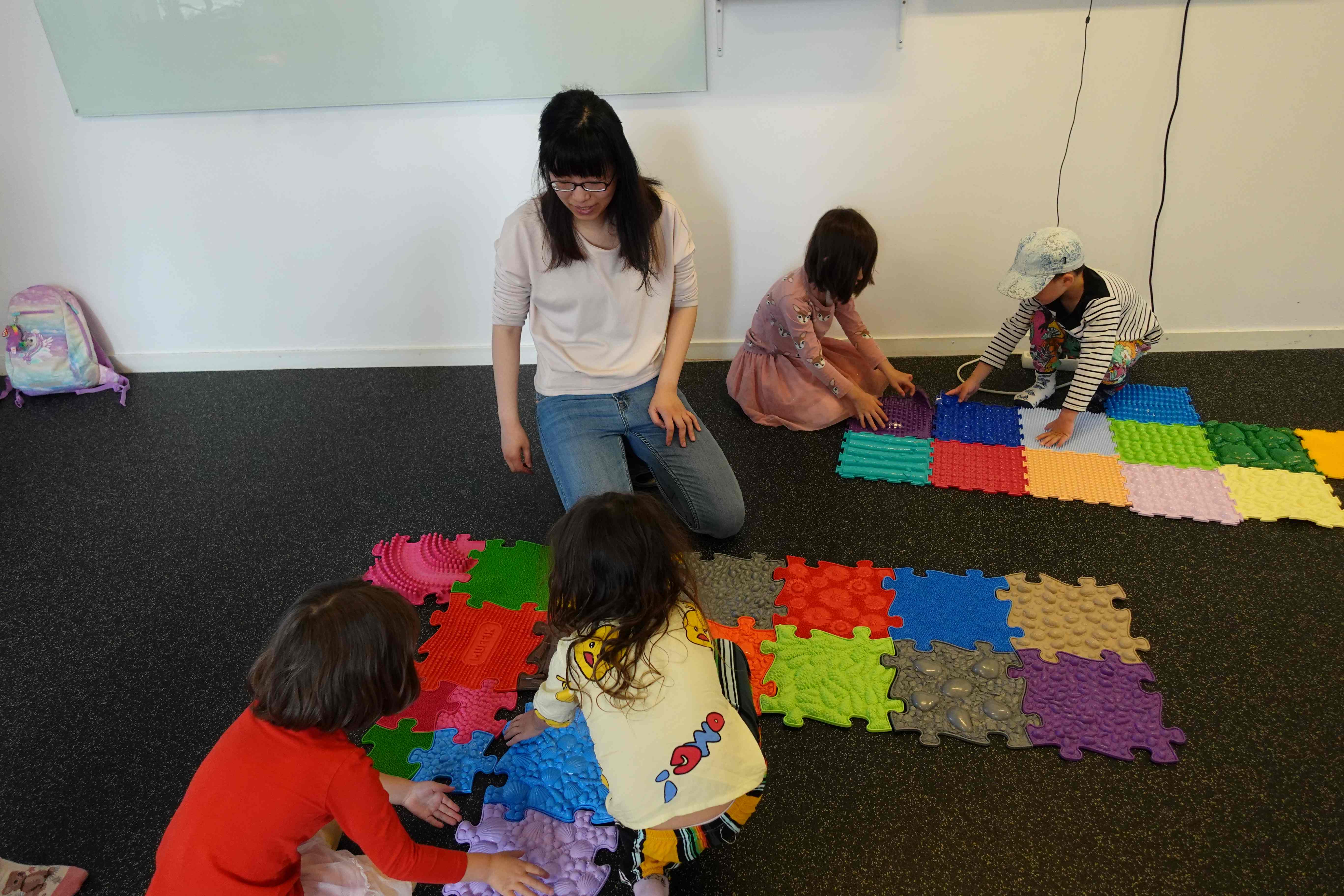 孩子透過巧拼按摩墊刺激身體感官並學習顏色主題的中文