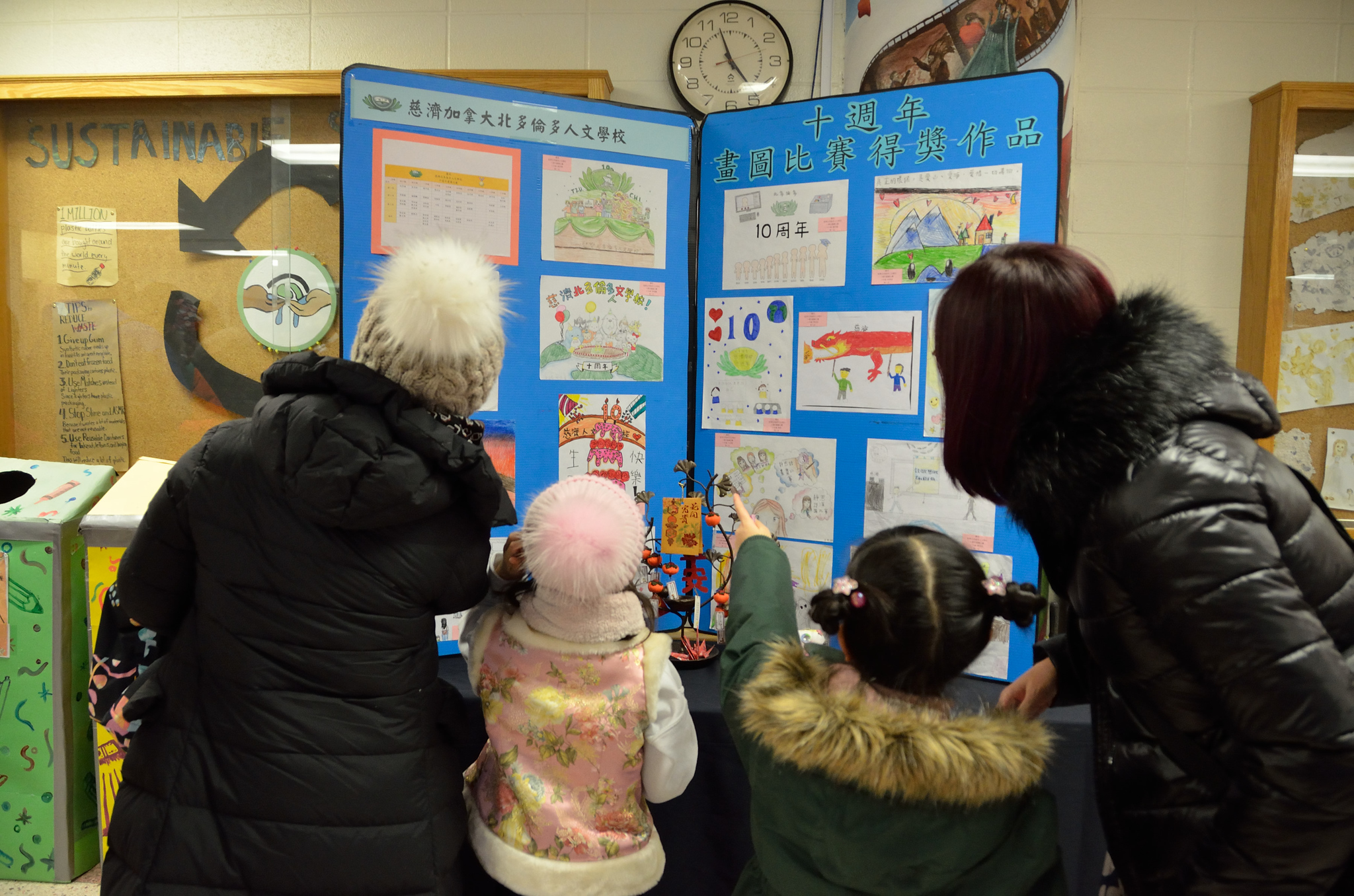 家長及學生們聚精會神的觀看慈濟北多倫多人文學校十週年畫圖比賽得獎名單及作品。
